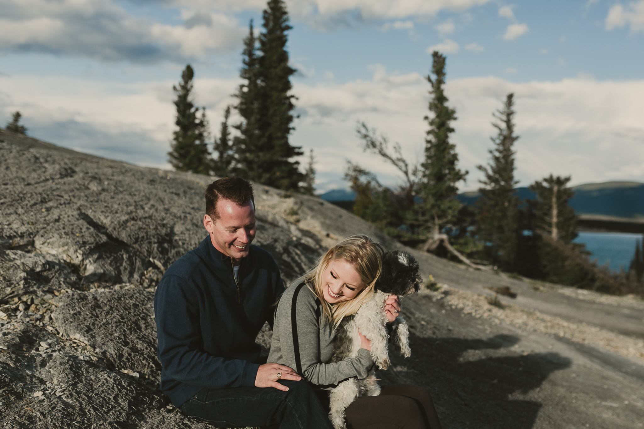 man and woman holding small dog in mountains