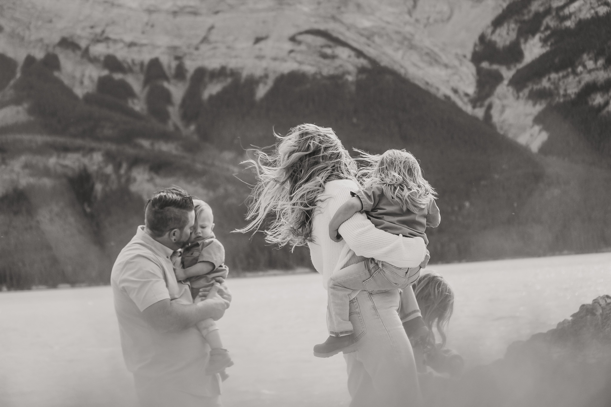 man and woman holding small children walking in the mountains