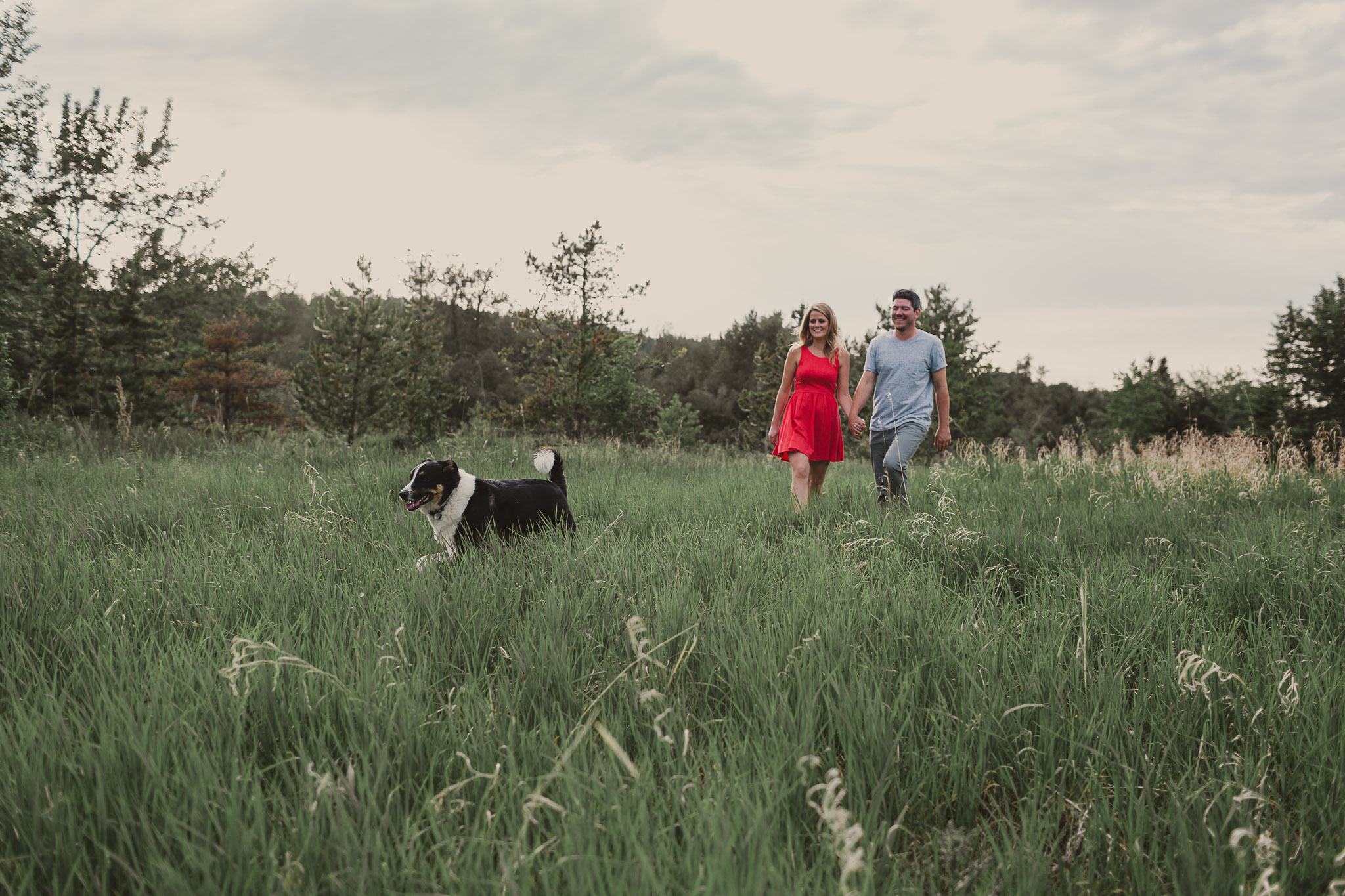 man and woman in red dress walking with dog