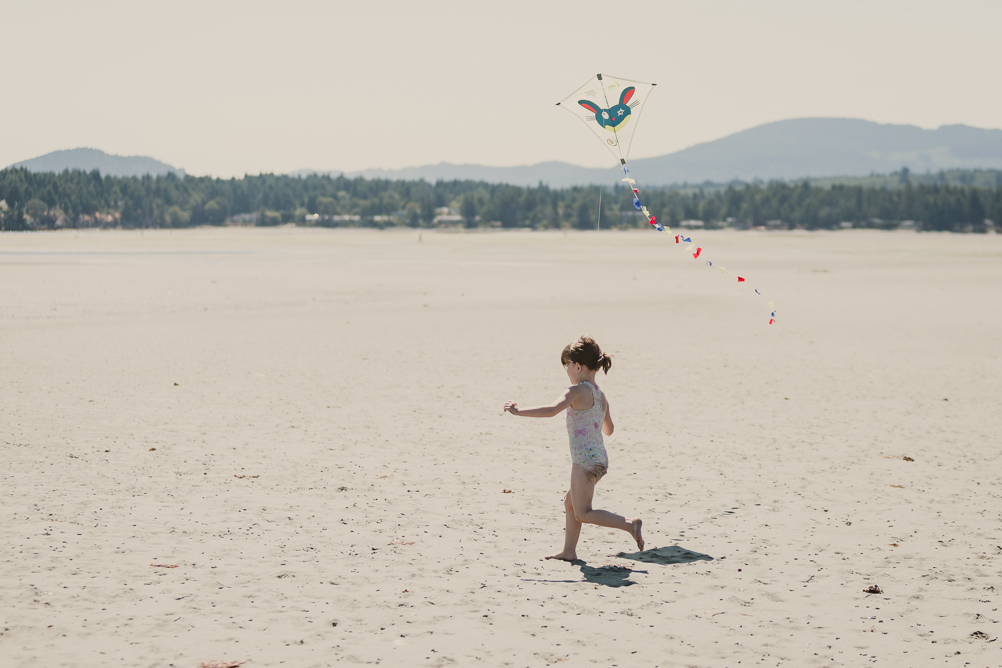 small girl flying kite on beach