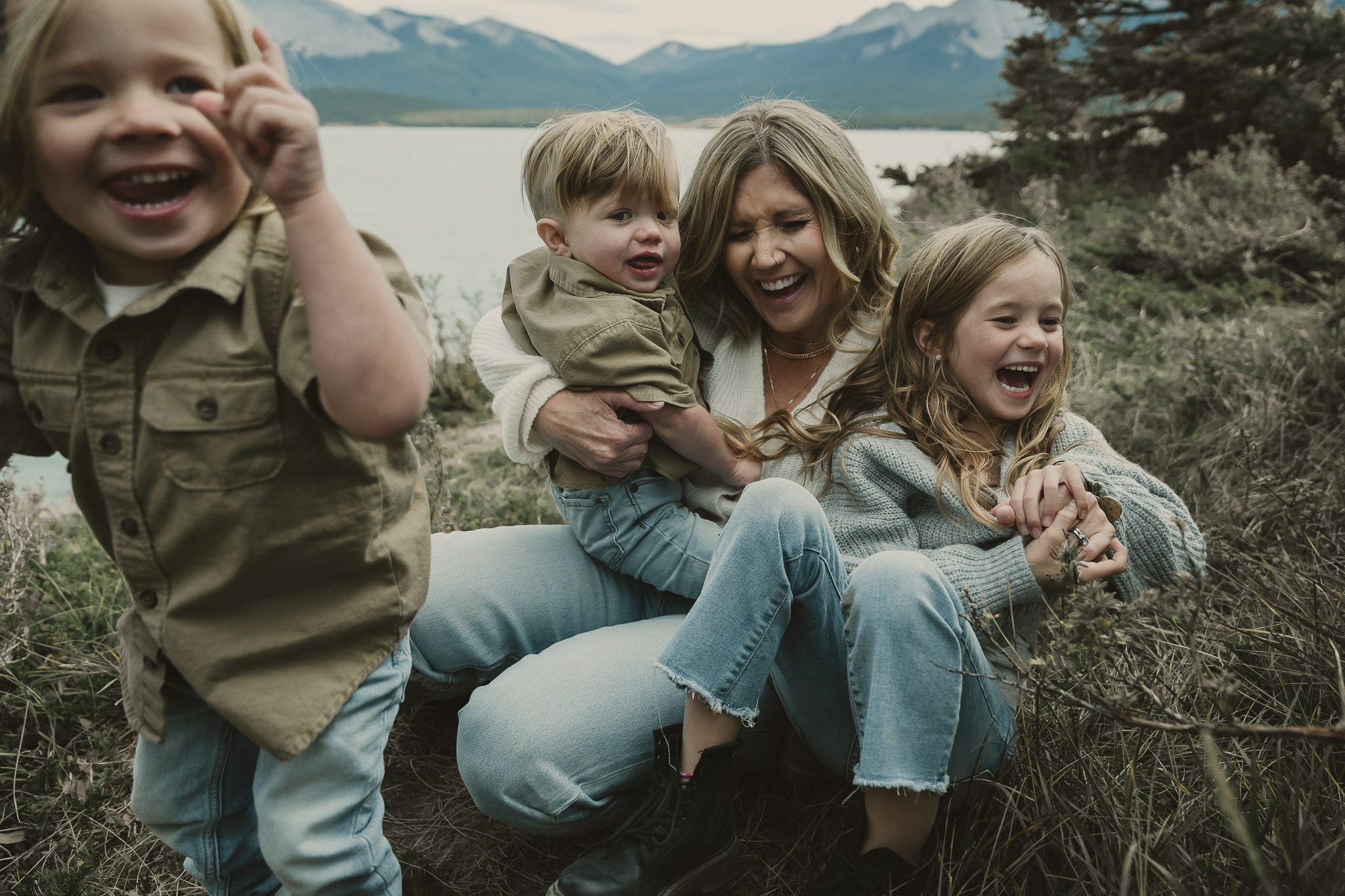 woman holding 2 children and one child standing