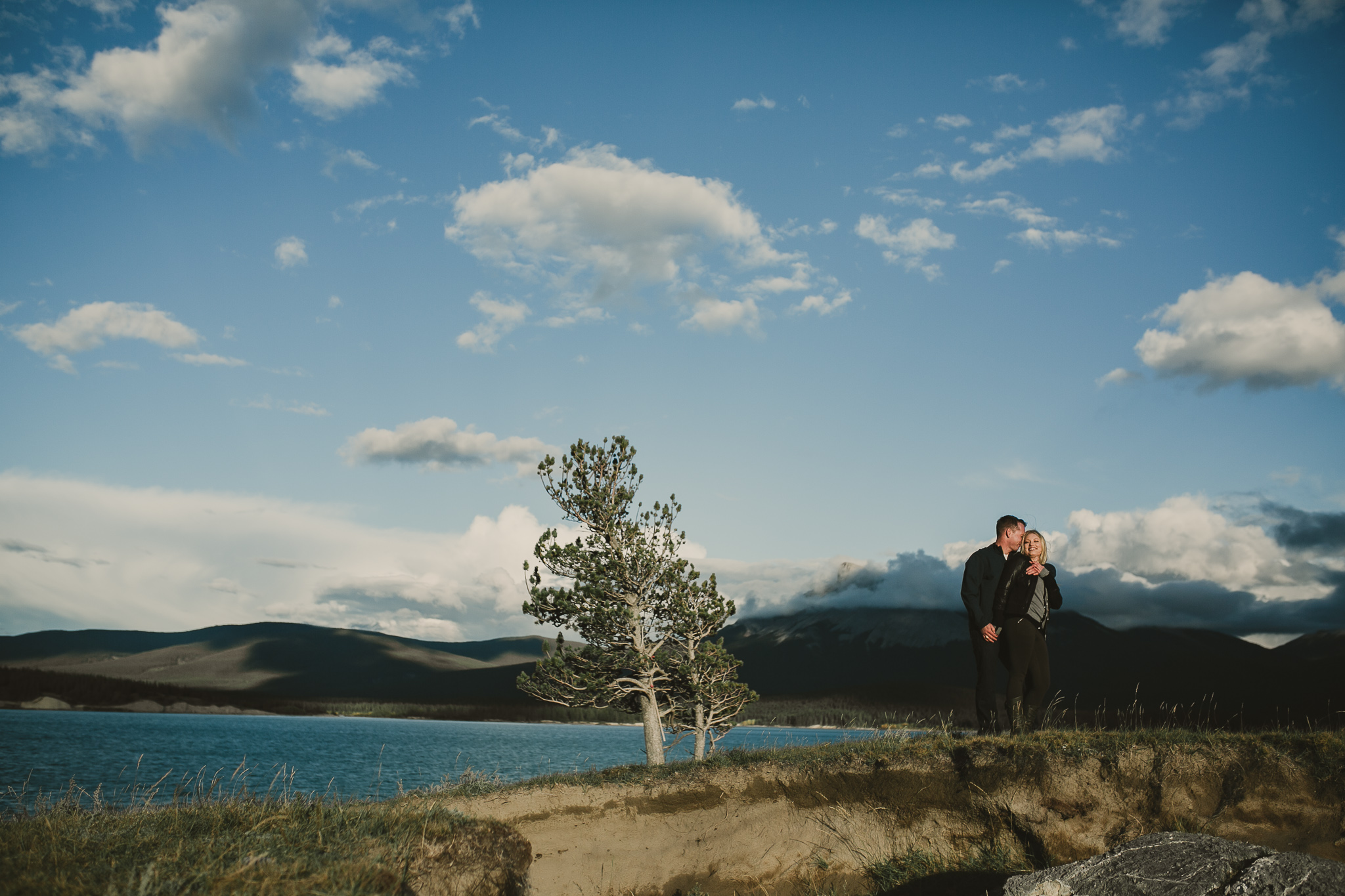 man and woman embracing in the mountains near a blue lake