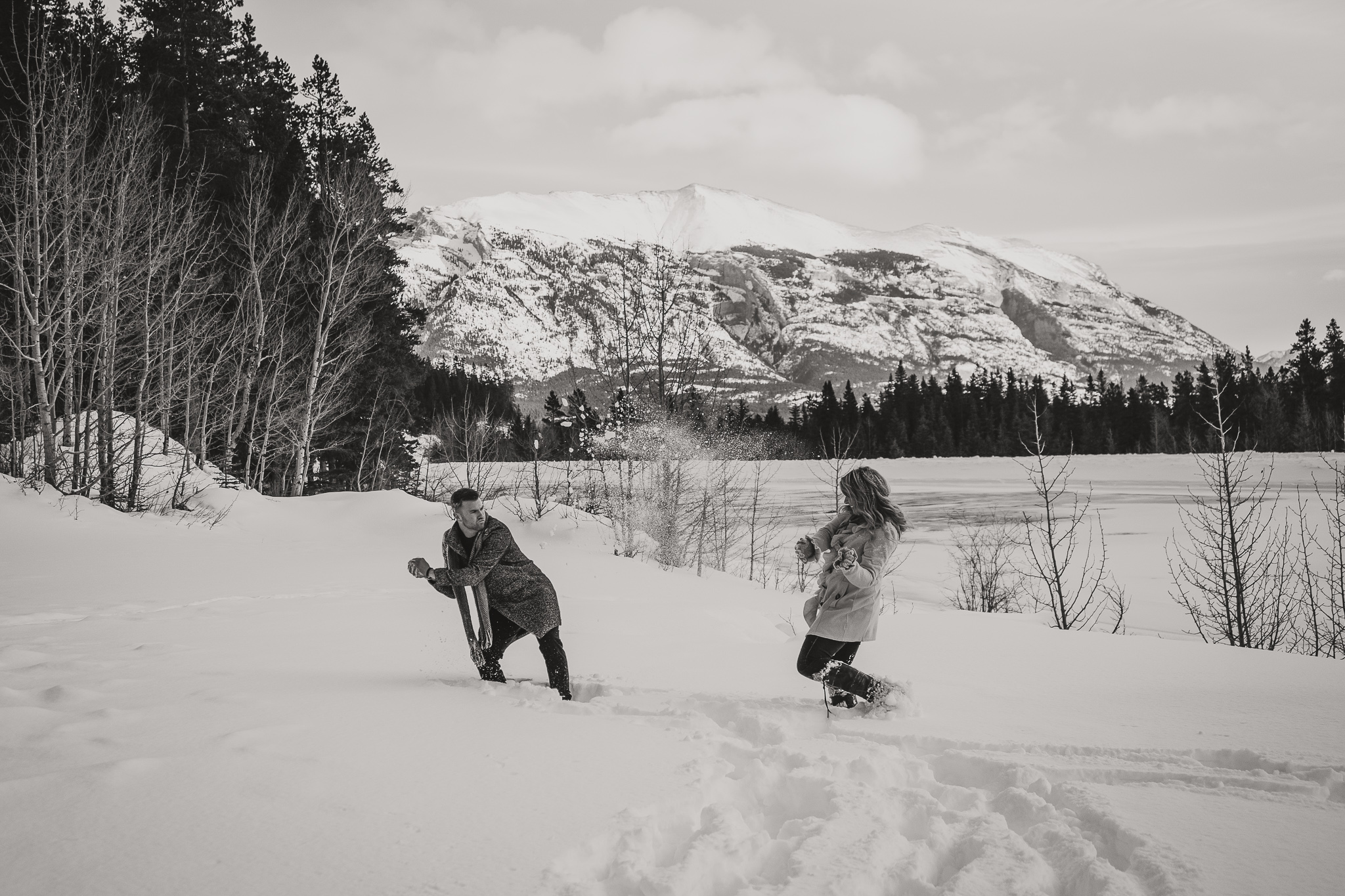 man and woman throwing snowballs in the mountains