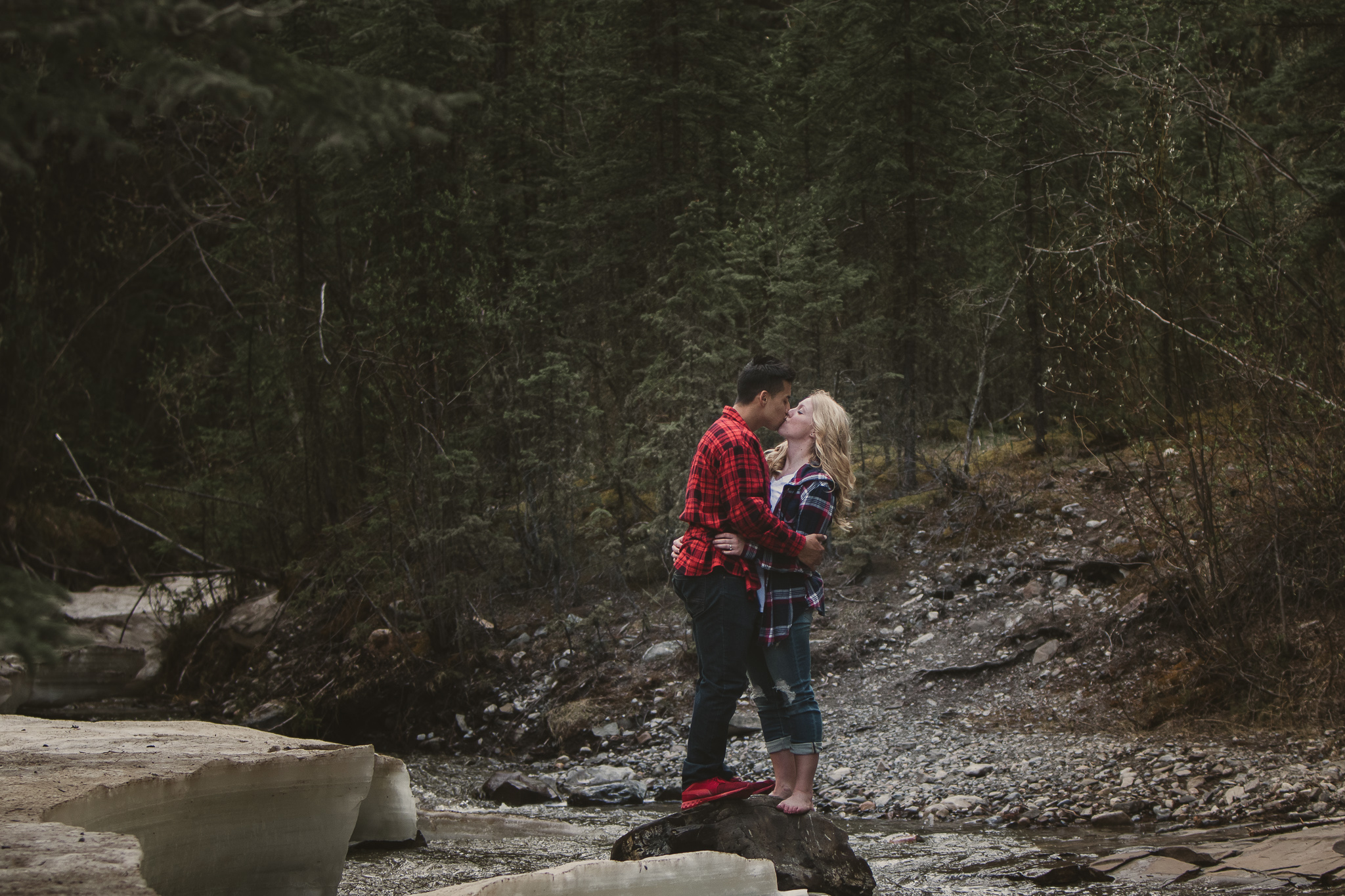 couple staning on a rock in the forest and hudding