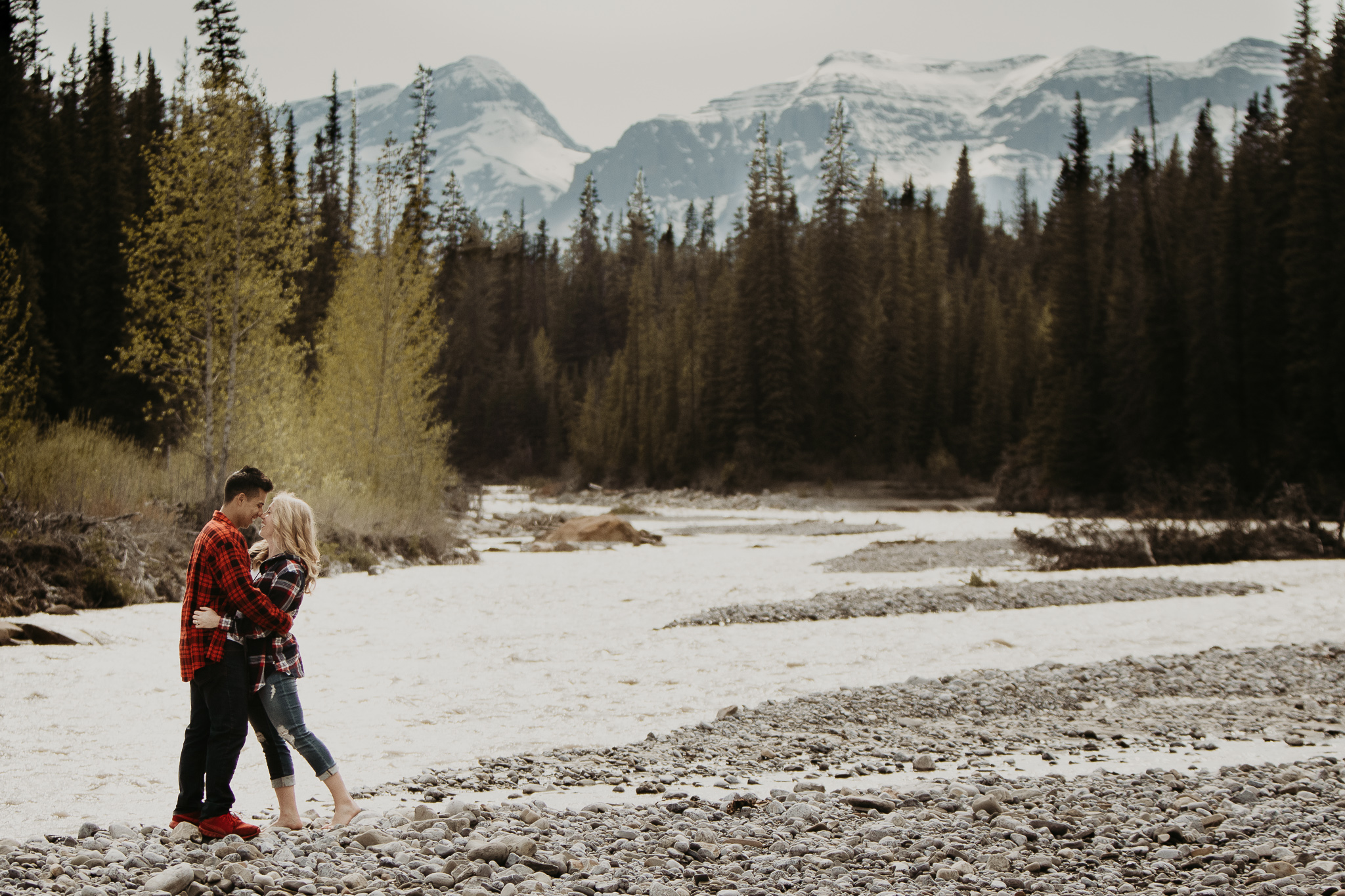 couple hugging by a river in the mountains