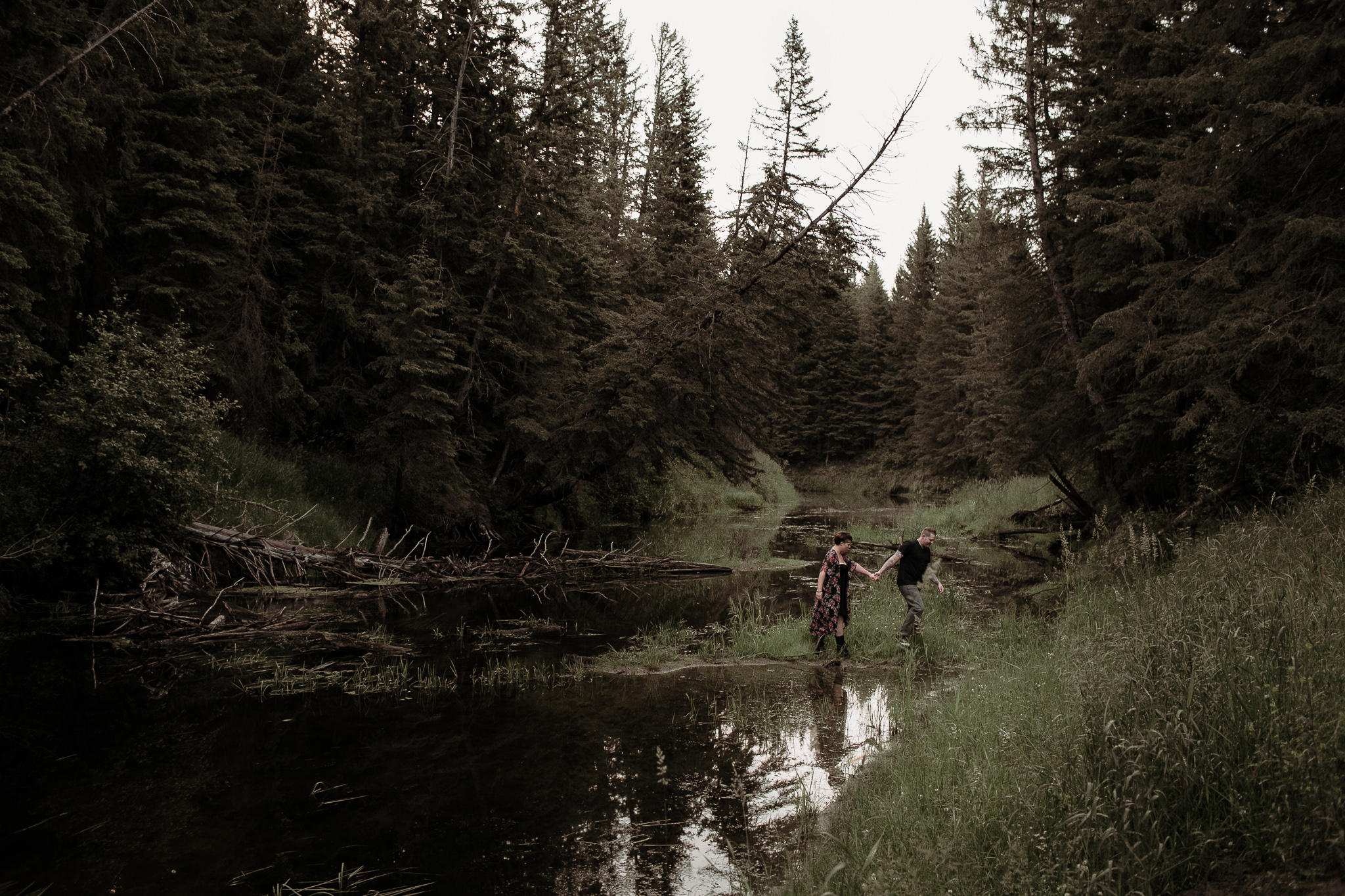 man and woman crossing creek