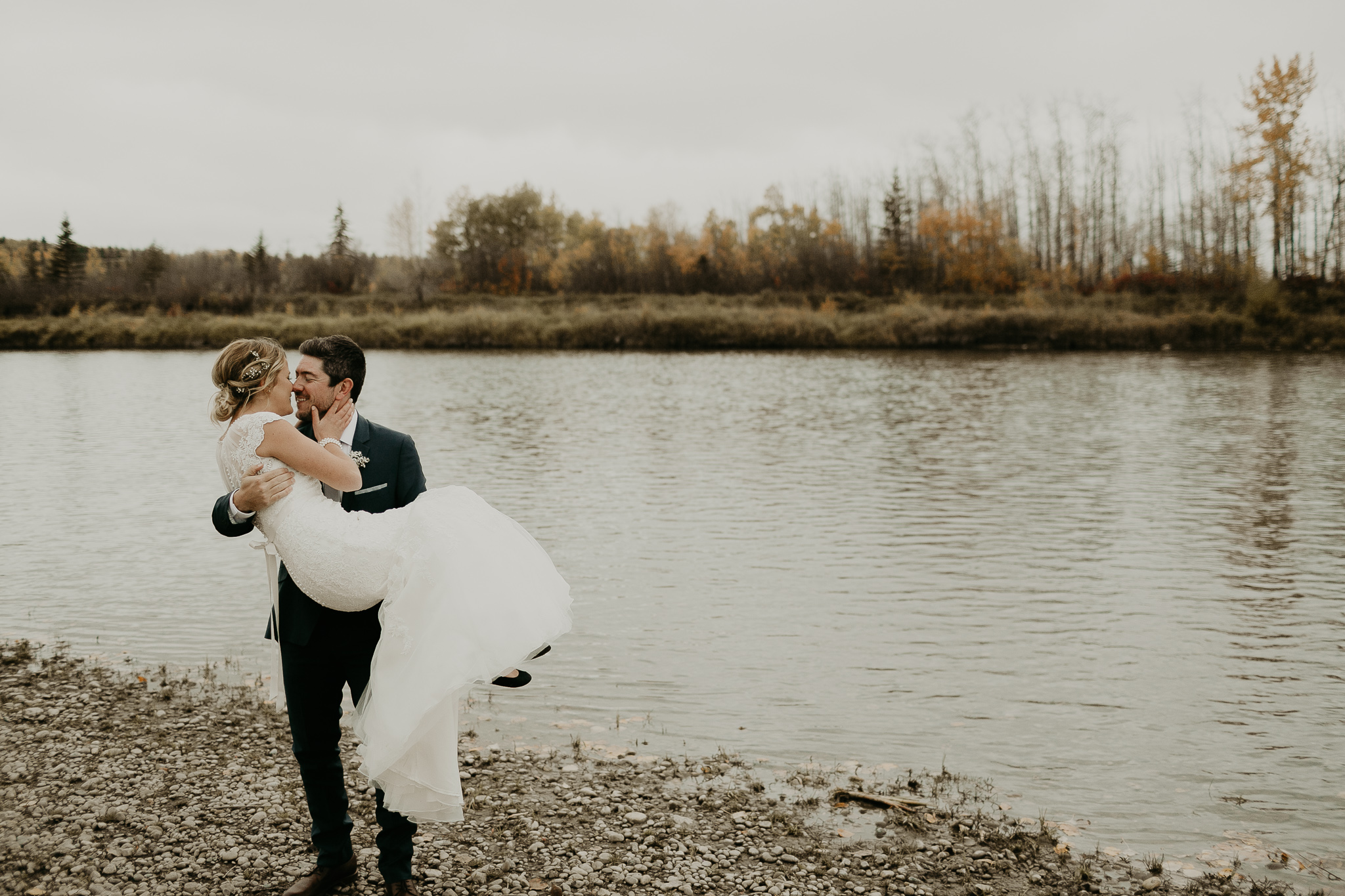 groom carrying a bride beside the river