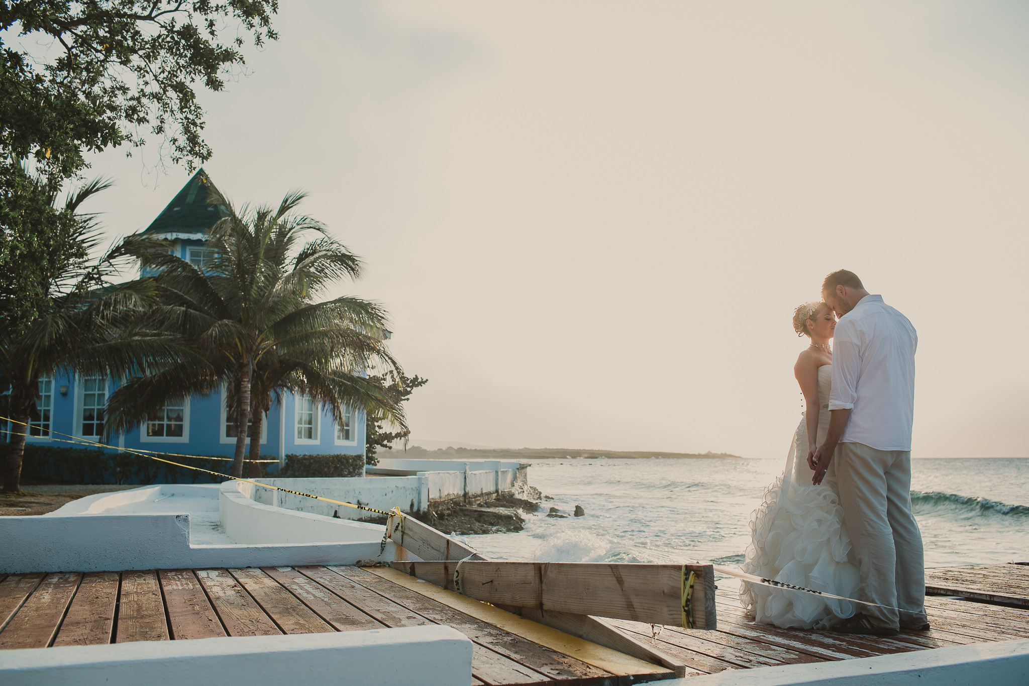 bride and groom kissing on a dock by the ocean