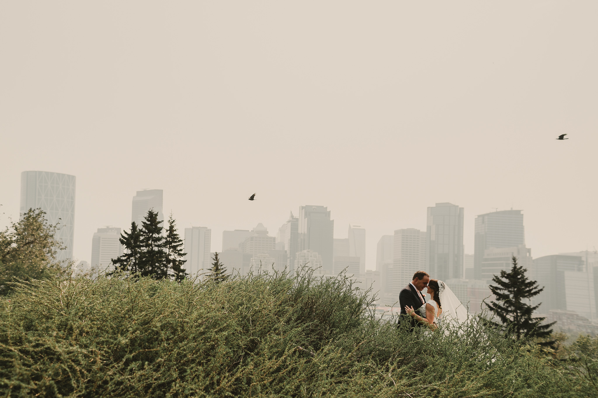 bride and groom kissing by a cityscape