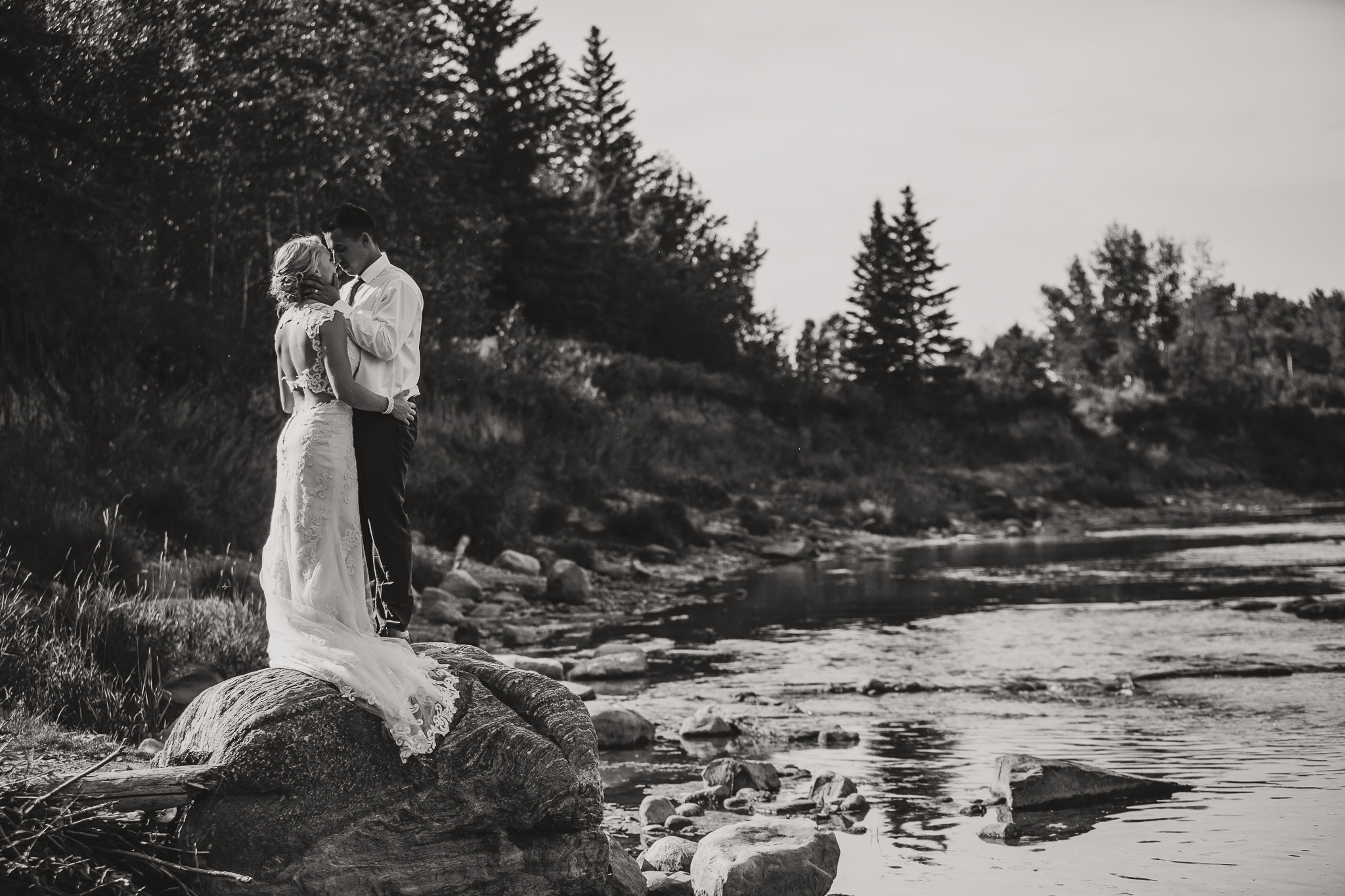 black and white wedding couple standing on a rock in the river