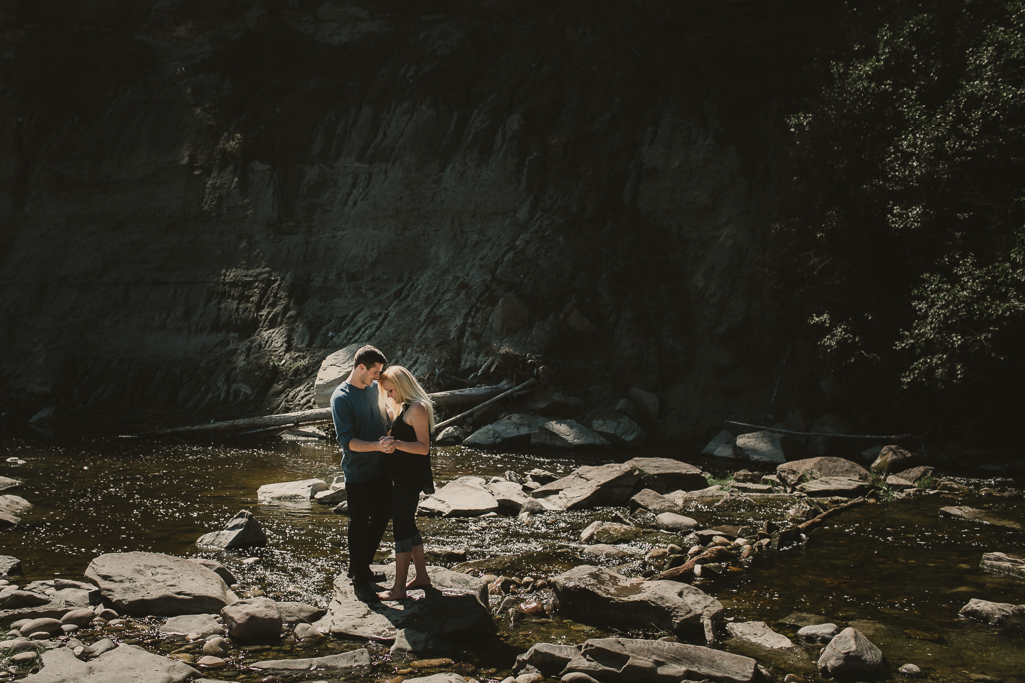 man and woan embrace on a rock in the river