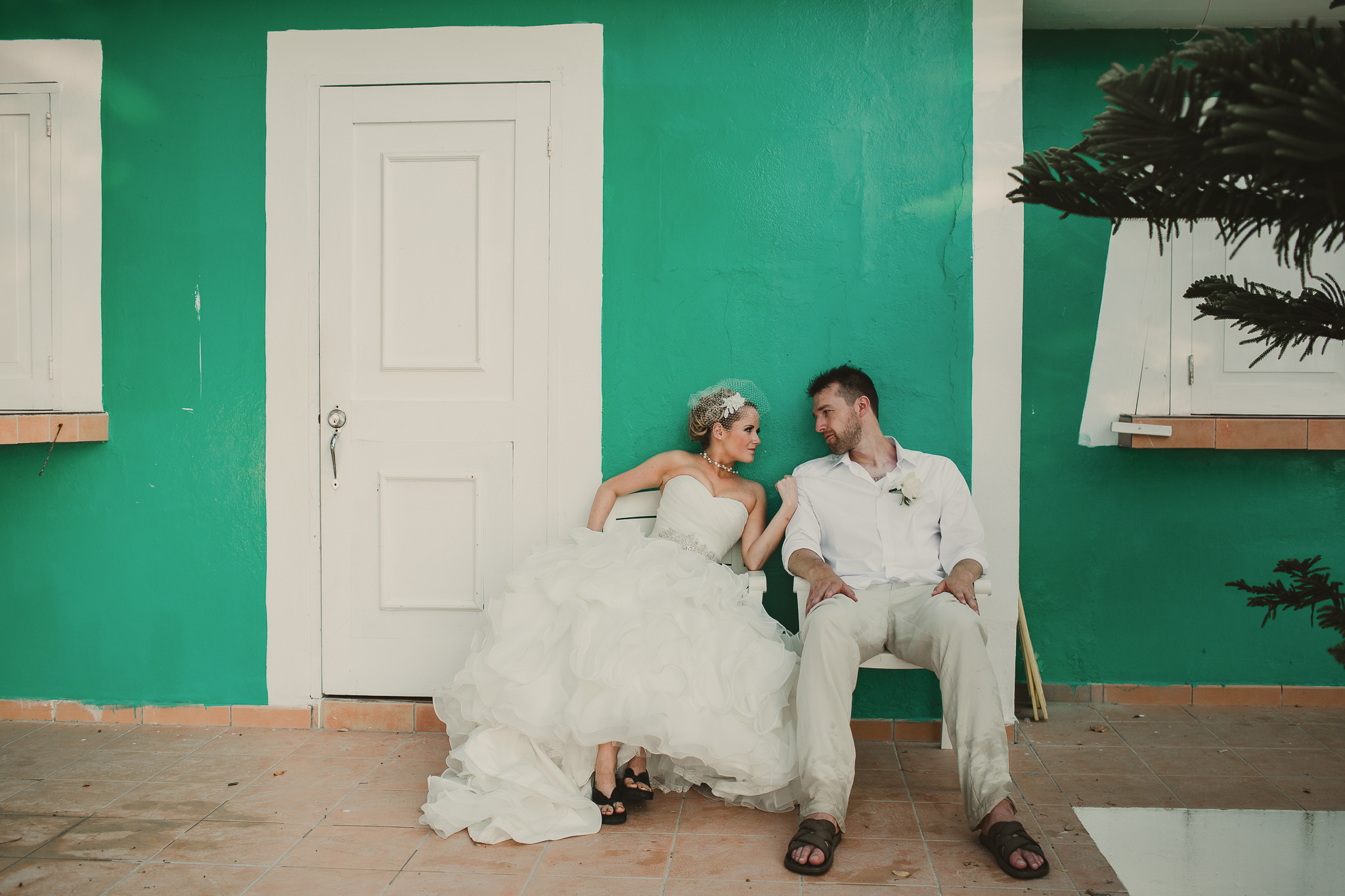 bride and groom sitting in front of a turquoise bulding