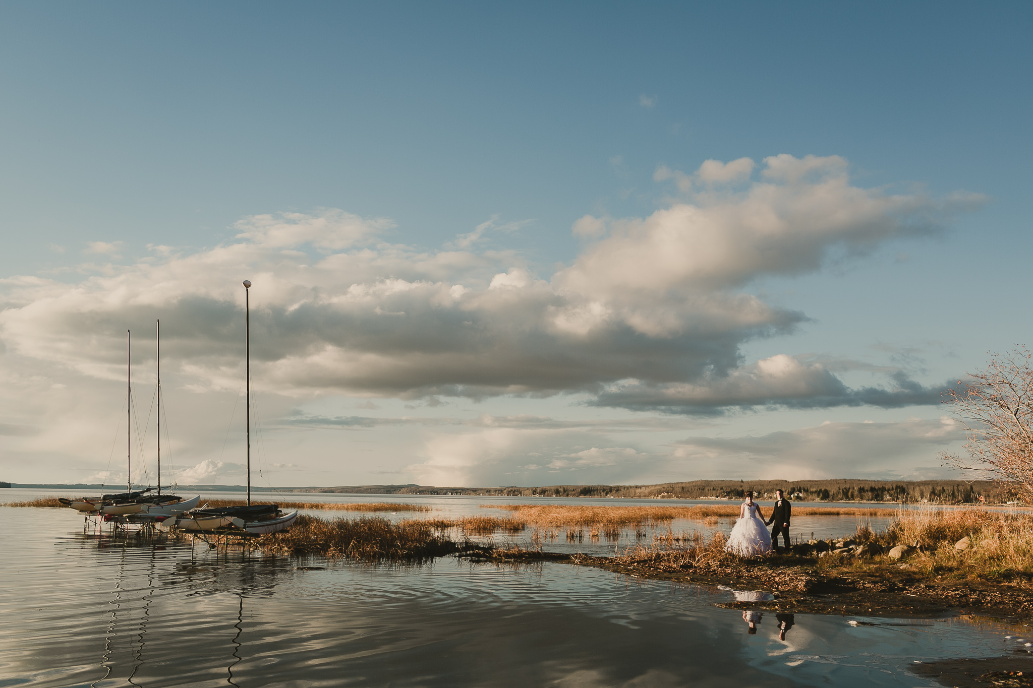 bride and groom standing by boats