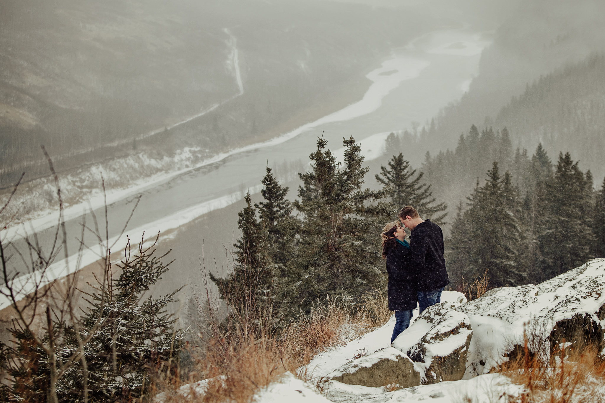 man and woman embrace near river valley