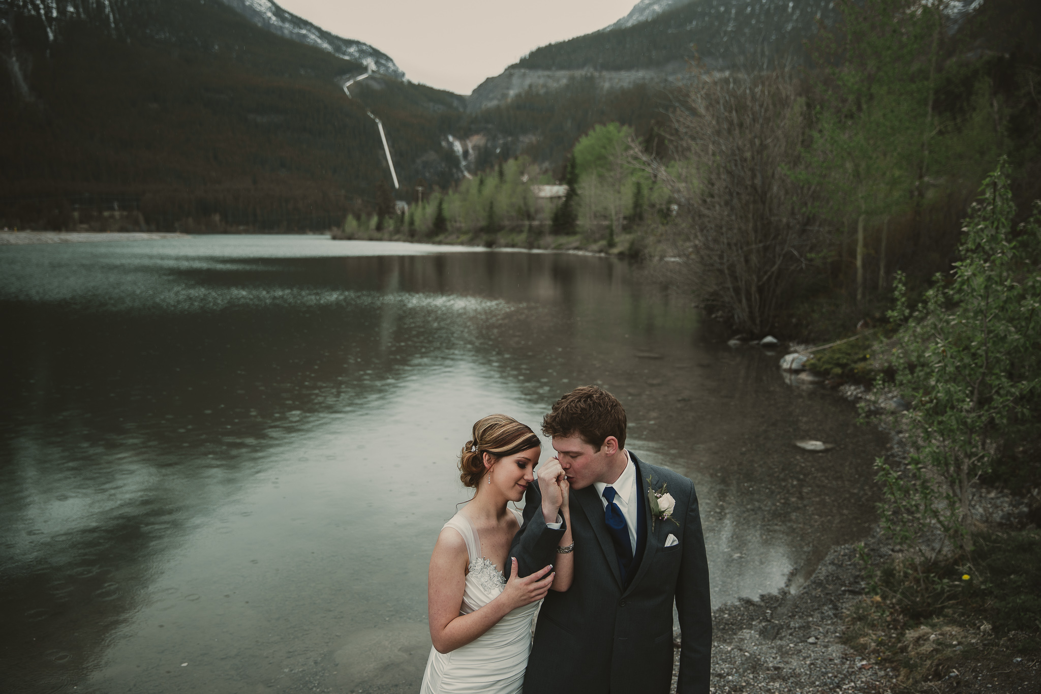 man kissing woman's hand in the mountains