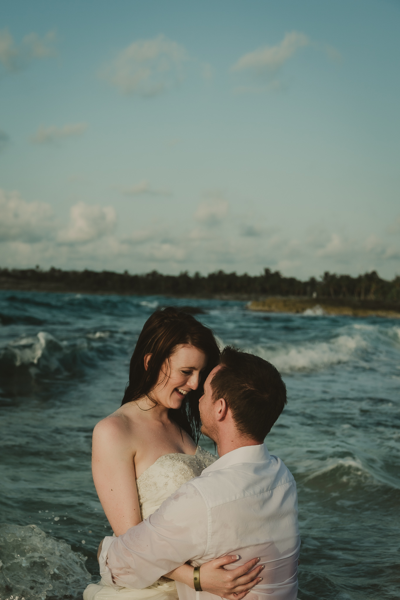 couple sitting in the ocean and looking at one another