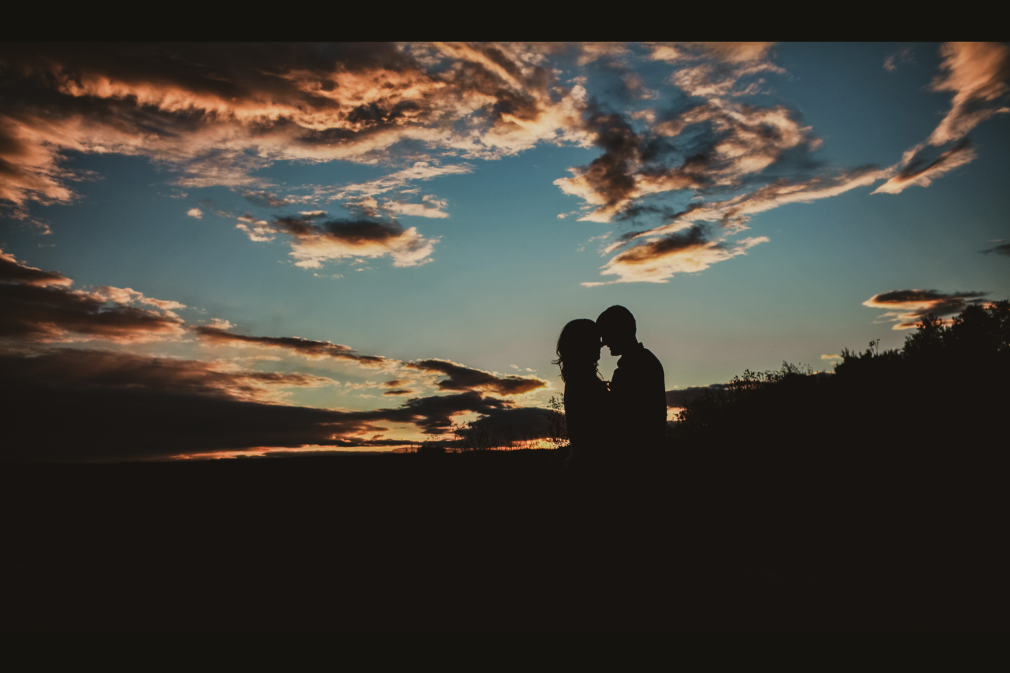 man and woman kiss at sunset