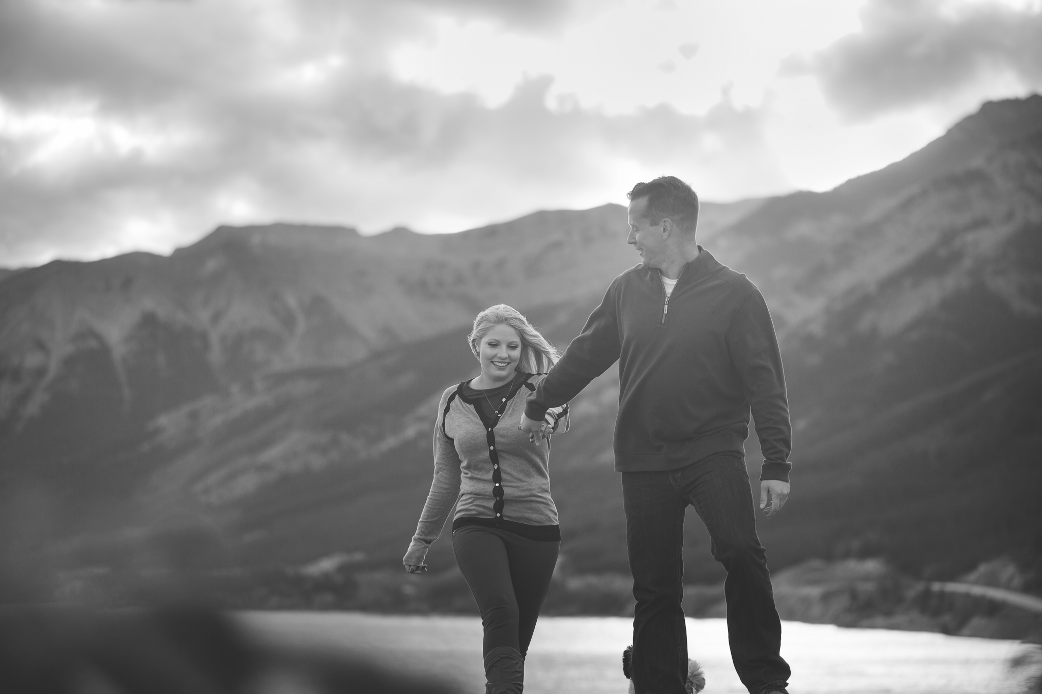 man leads a woman up a mountain holding hands black and white