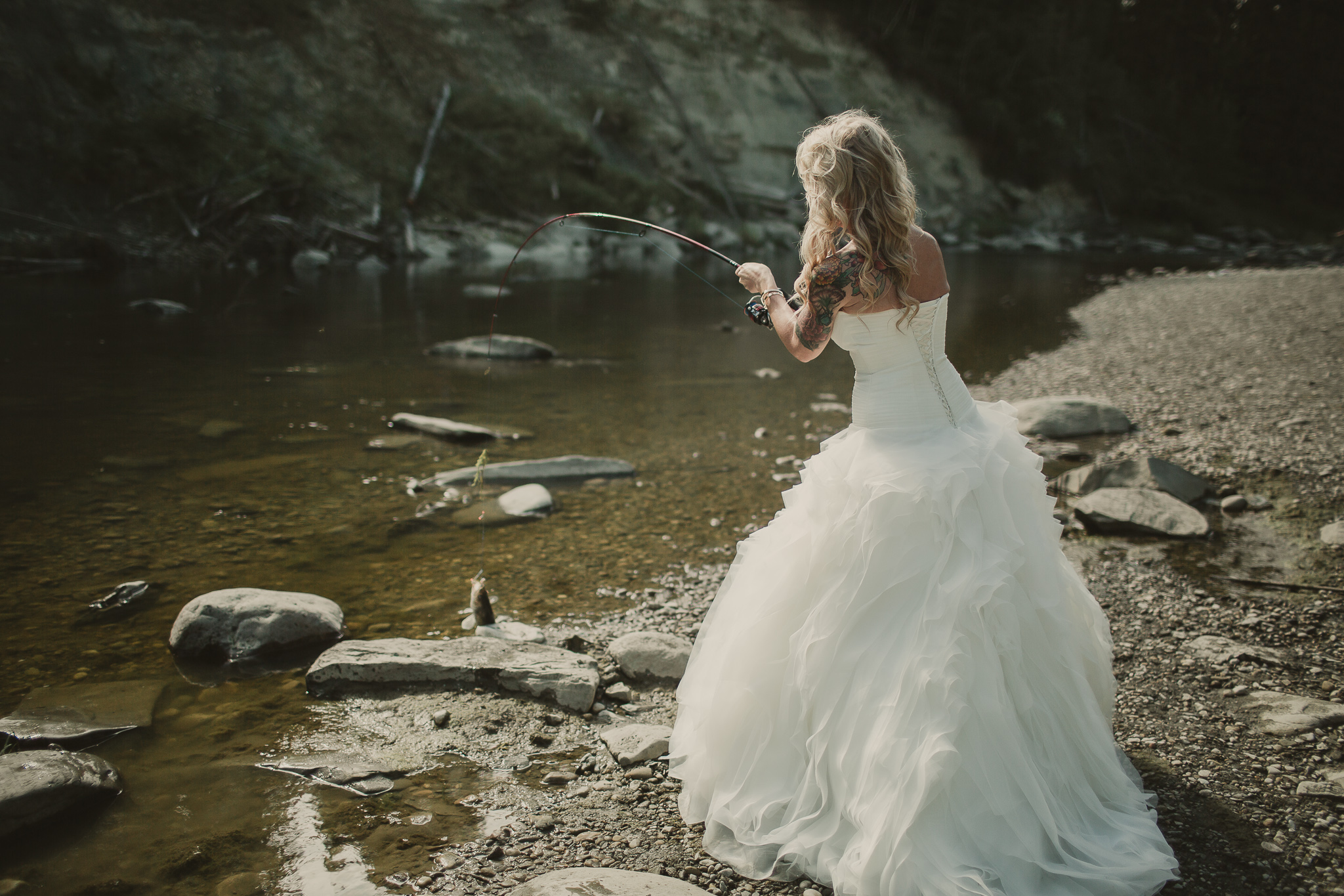 woman in a long white dress with a fish on her fishing rod