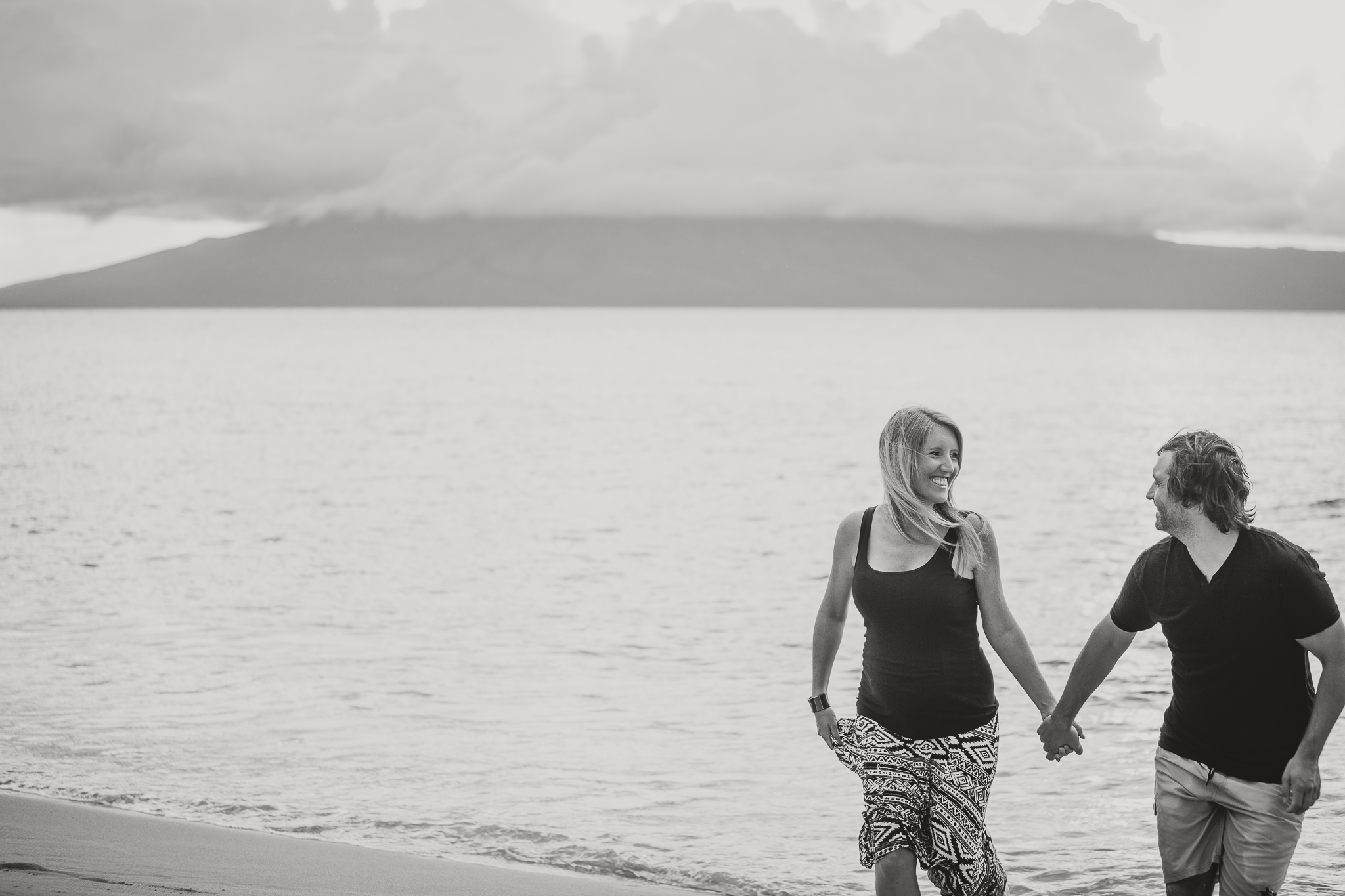 man and woman run on a beach black and white