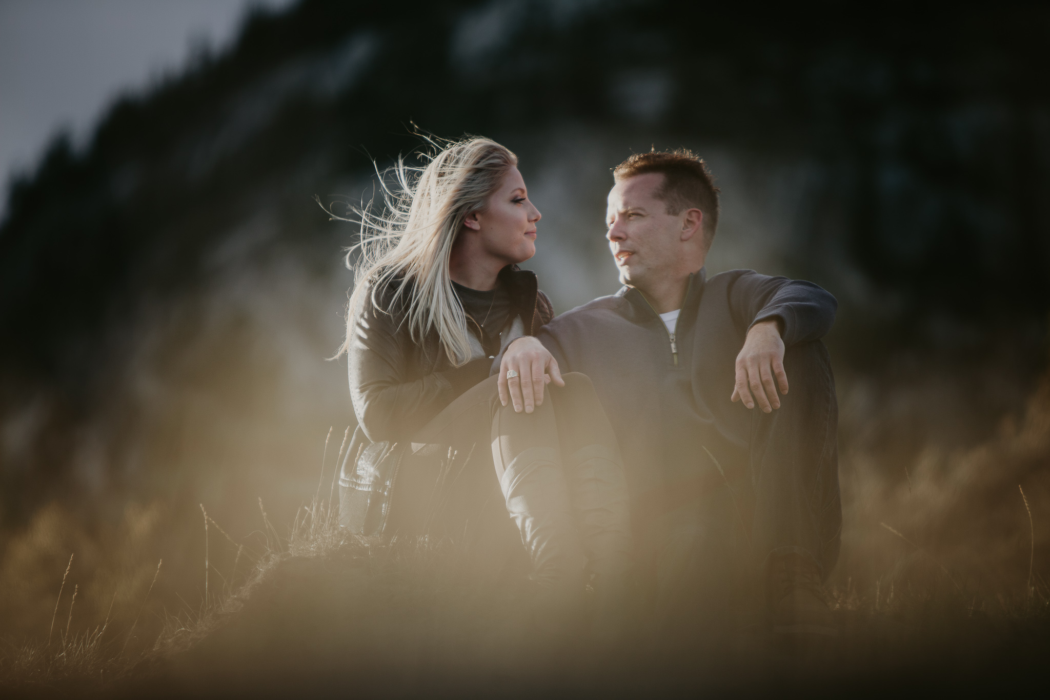 woman with wind blown hair looks at man in the mountains