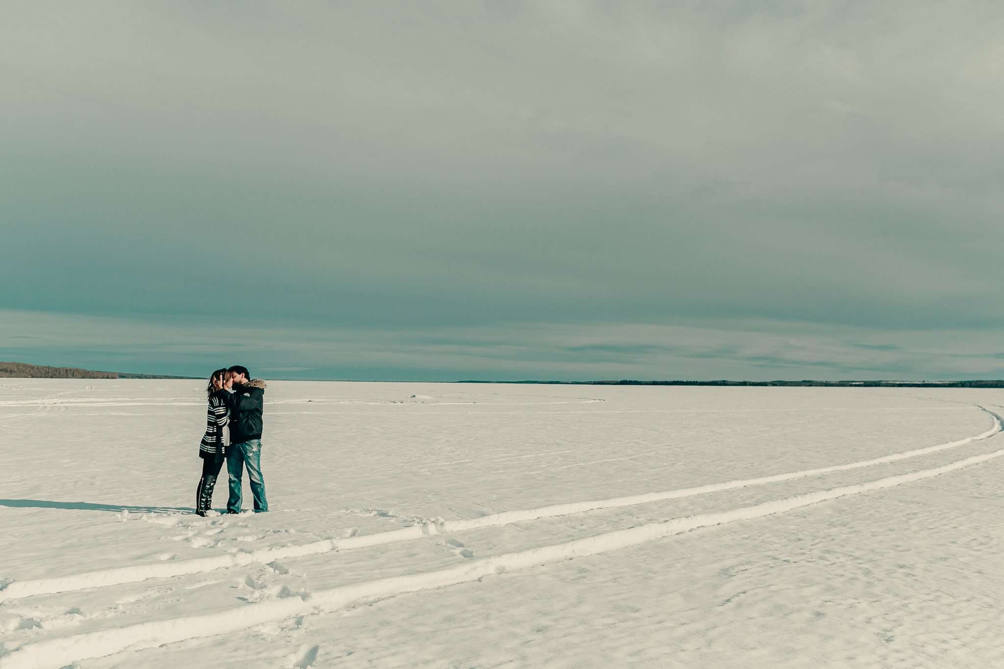 man and woman stand and kiss in the snow