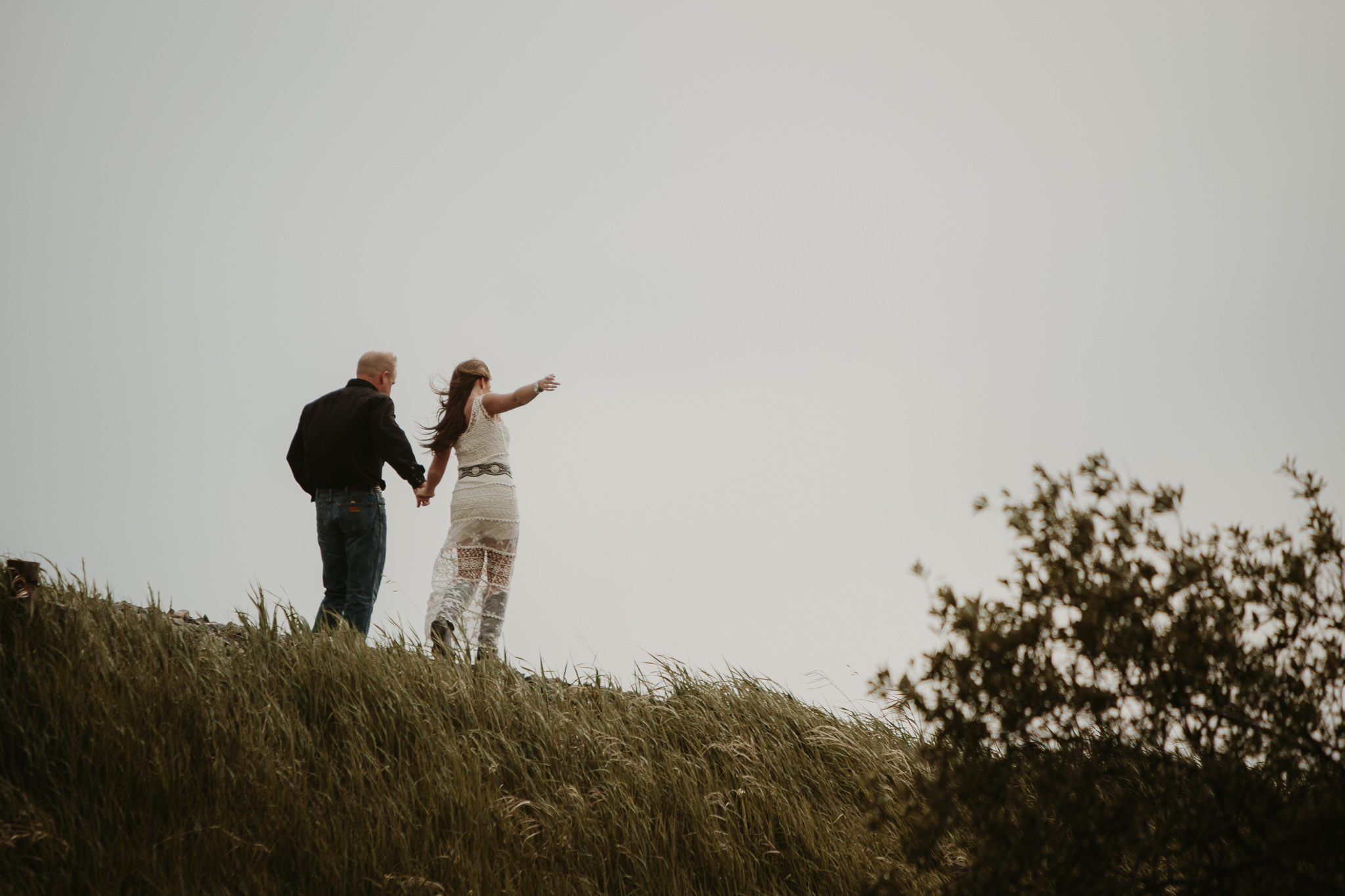 couple walk away on railway tracks holding hands