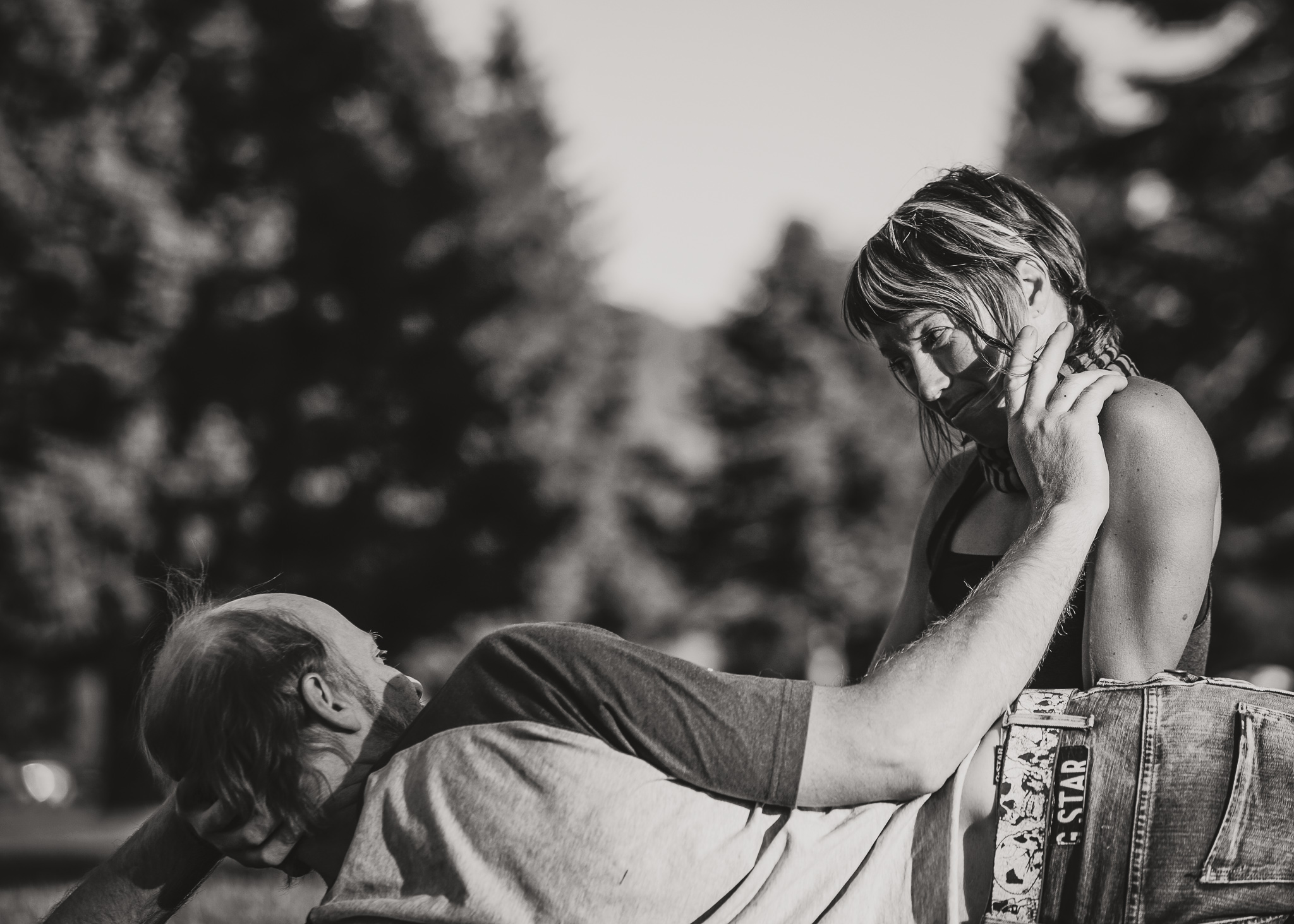 man laying on ground brushes hair from woman's eyes