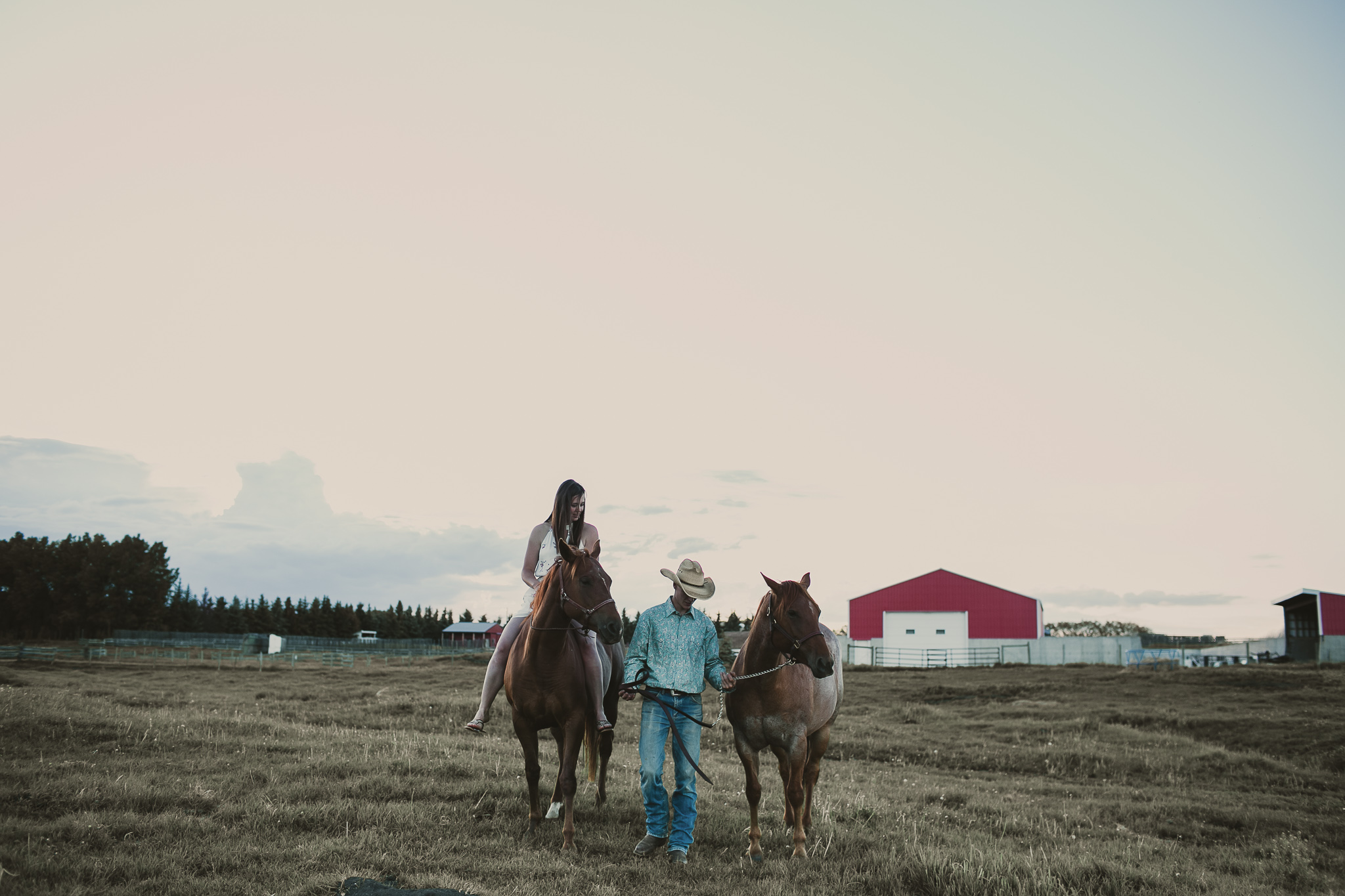 man leads a woman and 2 horses