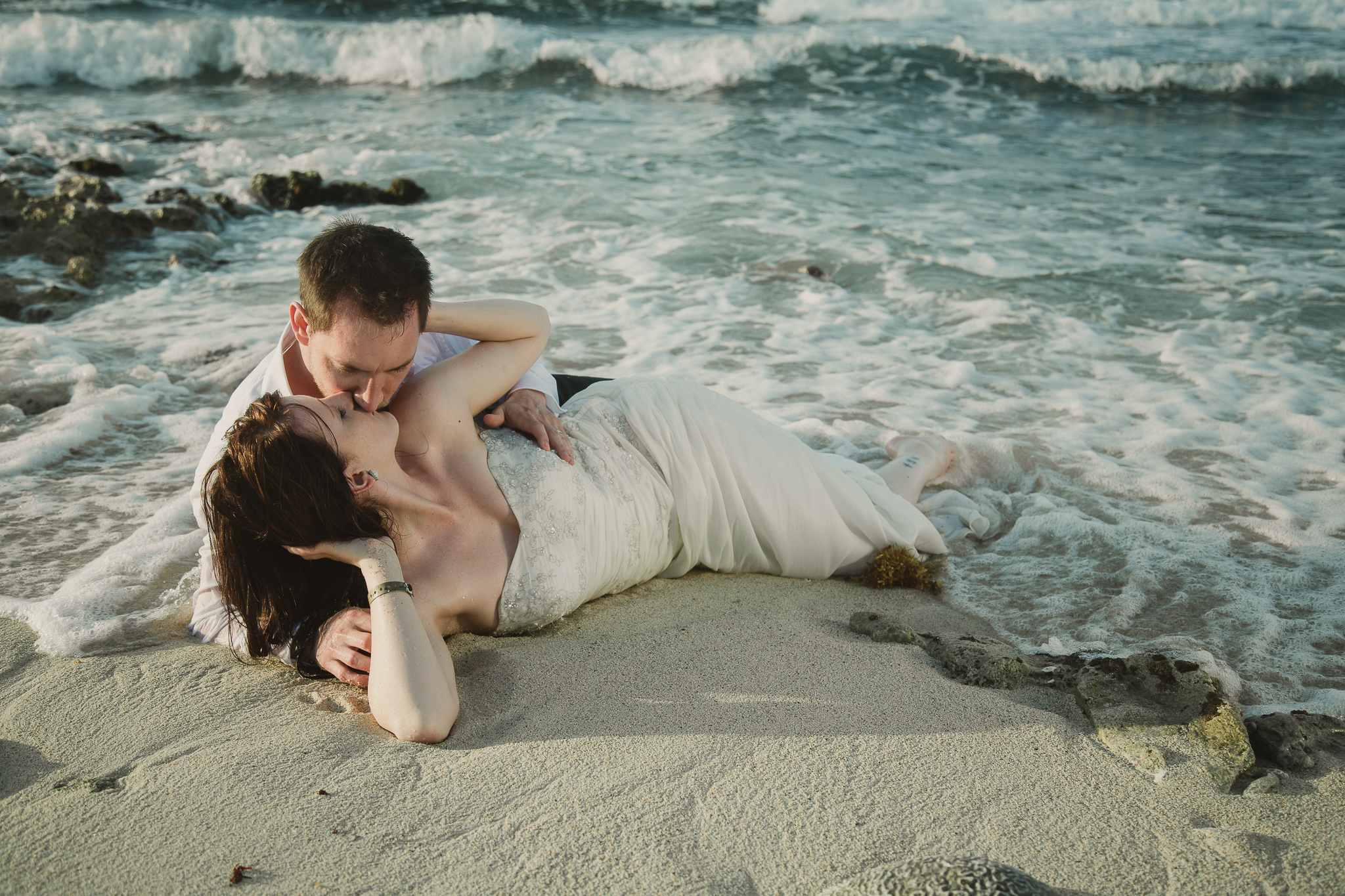 wedding couple laying on the beach