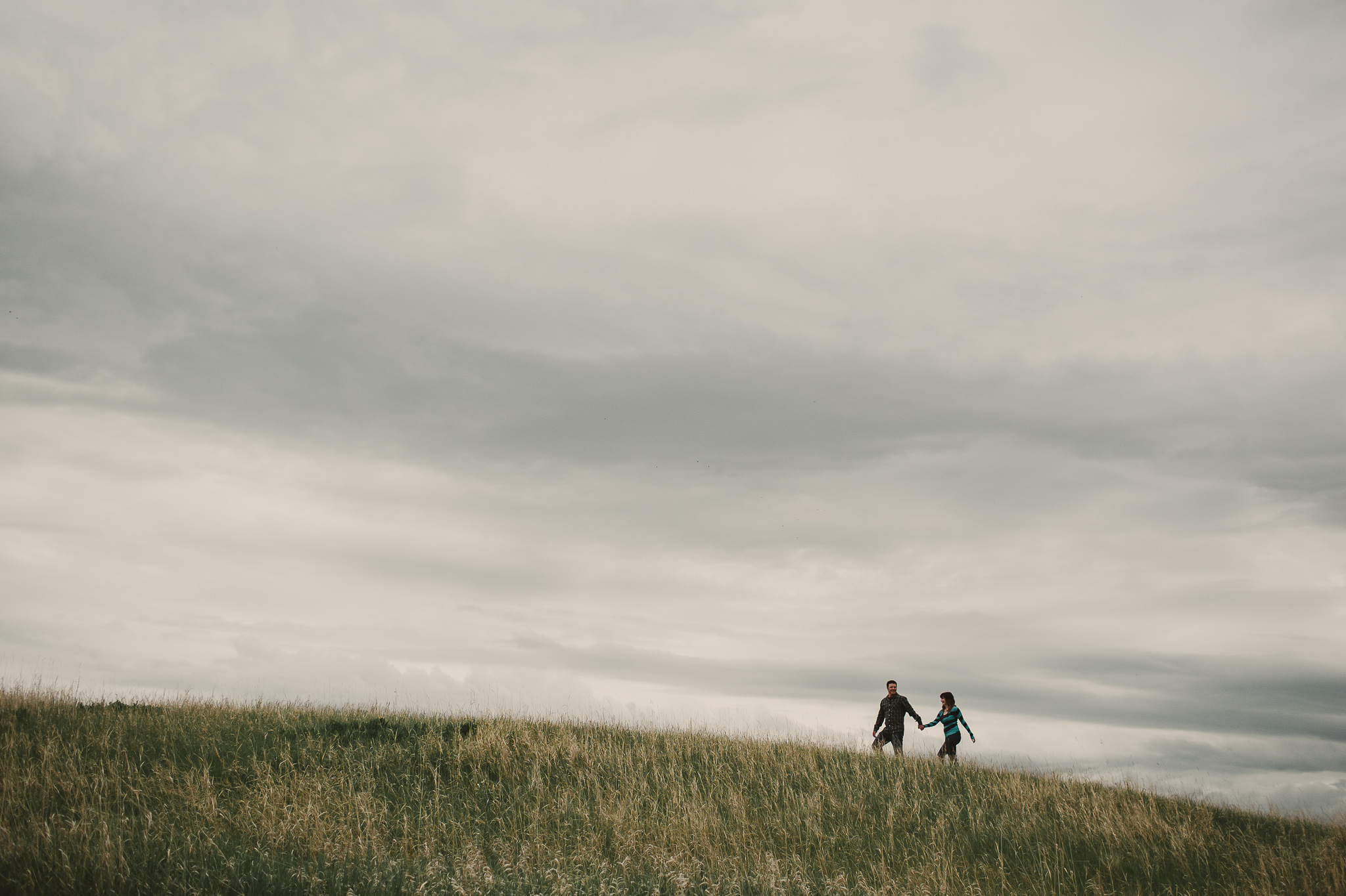 couple walk across hill holding hands