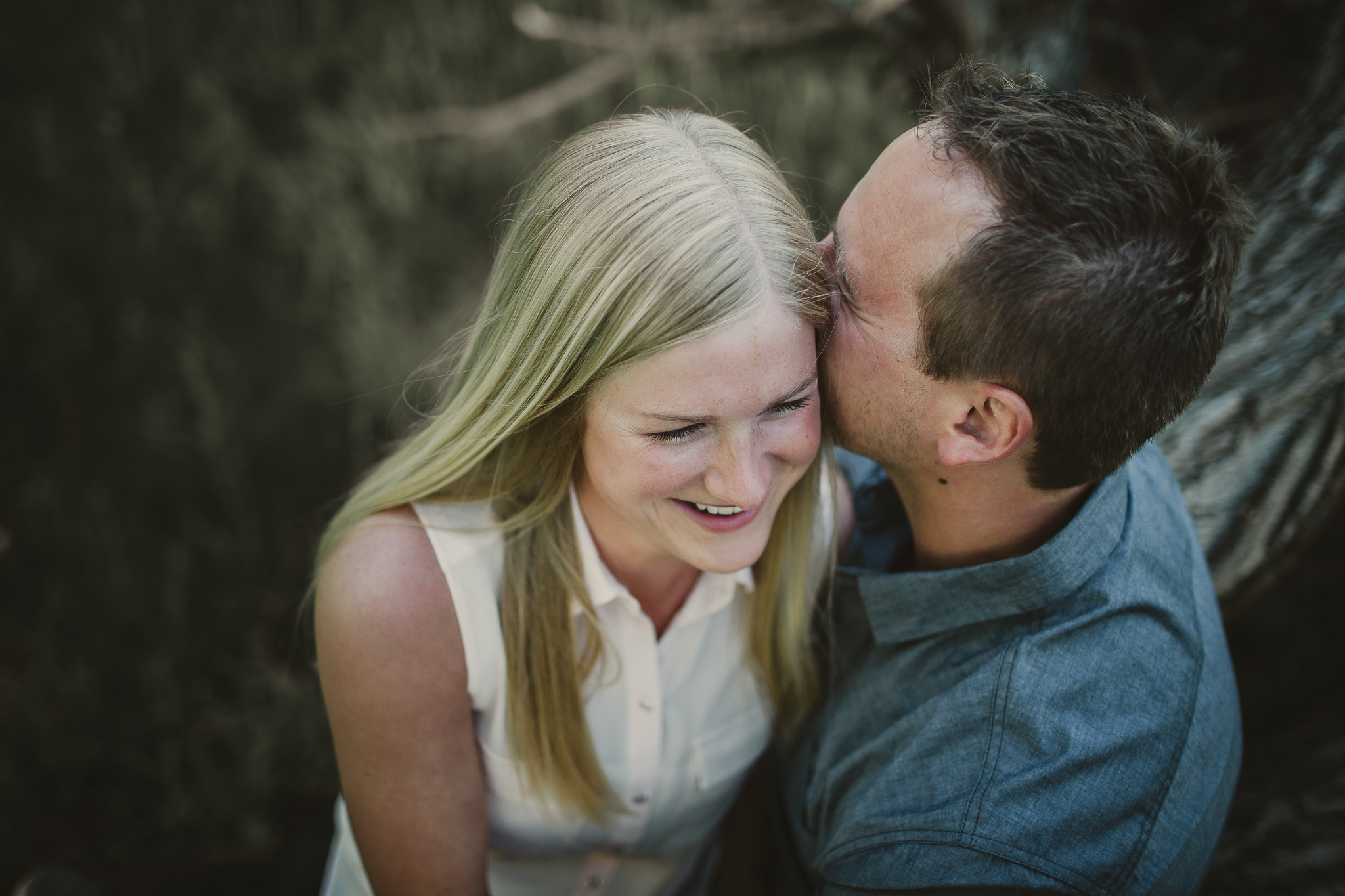 man whispers in smiling woman's ear