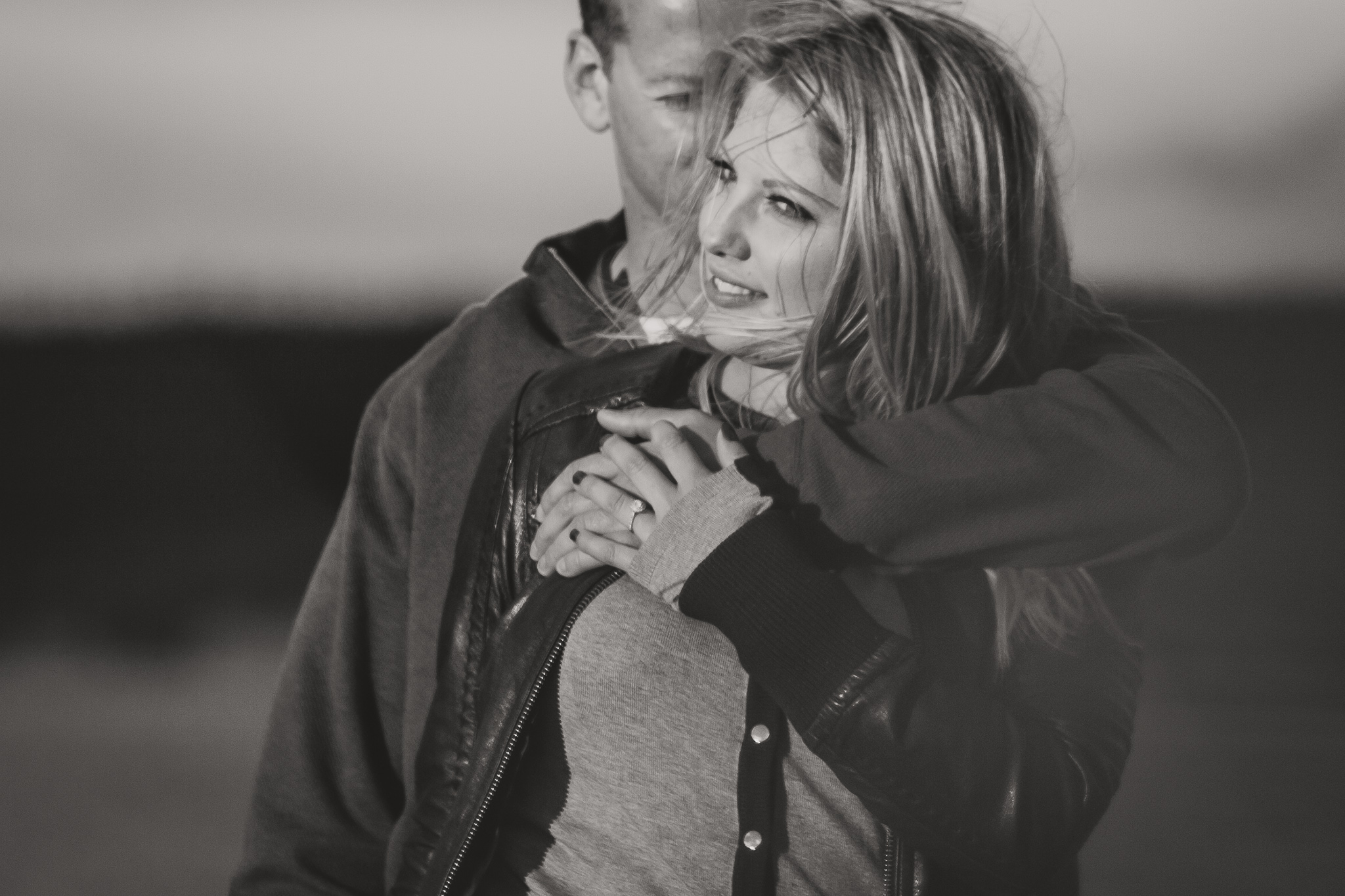 man holds woman from behind black and white