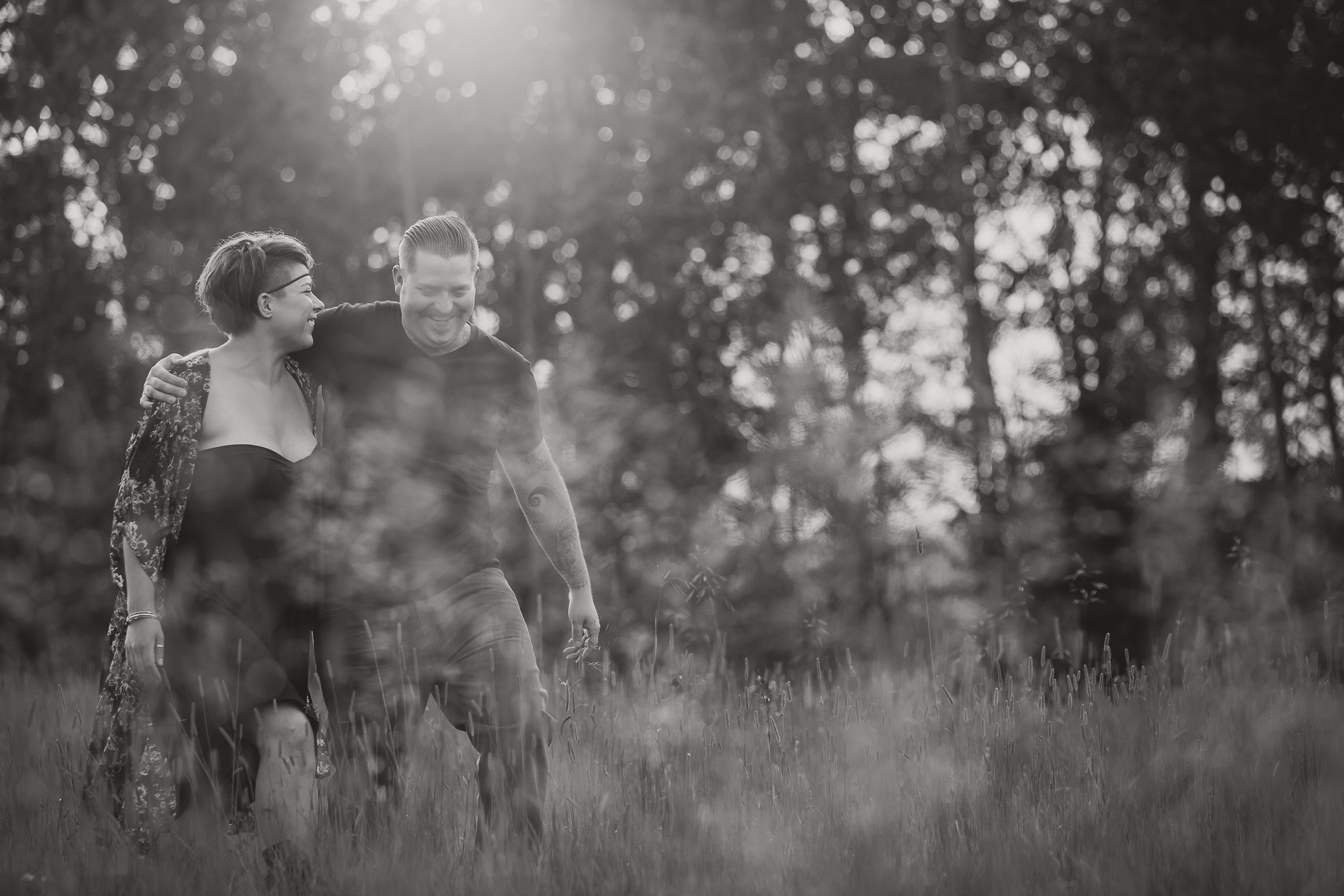 man with are around woman walking through tall grass black and white